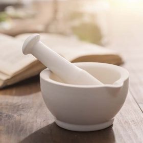 Mortar and pestle on wooden pharmacist table.